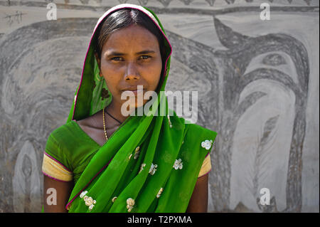 La donna in piedi di fronte a una casa decorata con dipinti murali. Questa forma di arte è chiamato Khovar arte ( India) Foto Stock