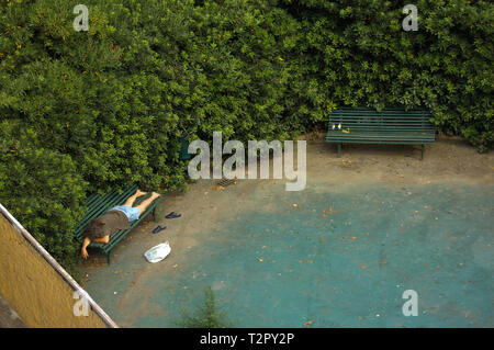 Senzatetto uomo dorme in un parco Foto Stock