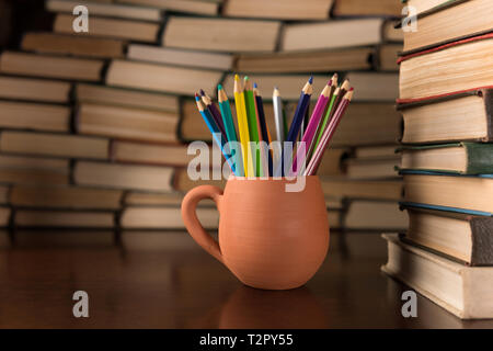 Matite colorate in una tazza sullo sfondo di libri Foto Stock