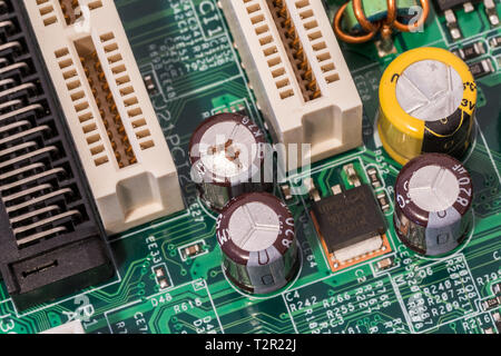 La foto mostra un condensatore su una scheda madre che è andato a male. È visibilmente il rigonfiamento in cima, e sembra essere perde così come corroso. Foto Stock