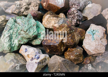 Grande pezzo di materie malachite tra altri frammenti di pietra alla mostra di minerali Foto Stock