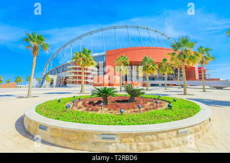 Doha, Qatar - 21 Febbraio 2019: palme e aiuole fiorite in Aspire Park con Khalifa dello Stadio Nazionale di Qatar, ospiterà 2022 Coppa del mondo. Completato Foto Stock