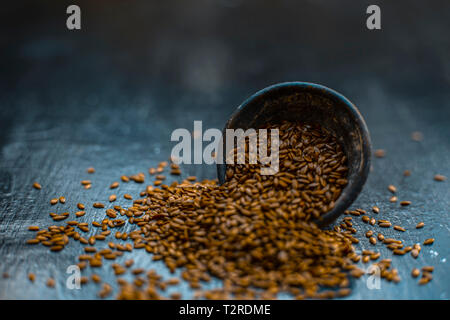 Close up di erba ayurvedica Alsi o ADSI o di semi di lino in un colorato nero ciotola di argilla su una superficie di legno usato in un molti farmaci ayurvedici. Foto Stock