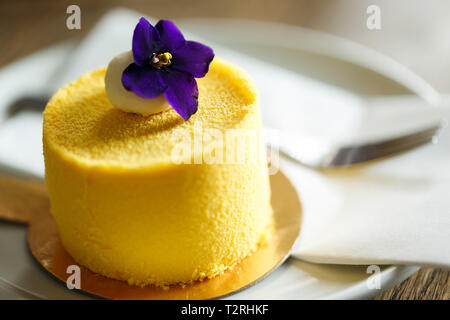 Deliziosi dessert con gusto di mango, decorata con violetta shot vicino vicino. dessert su un piattino bianco in un ristorante Foto Stock