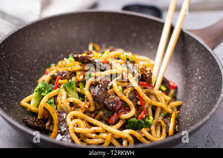 Udon Stir-Fry Tagliatelle con manzo e verdure in padella Wok su sfondo scuro Foto Stock