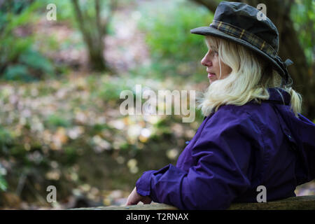 Shorne, Country Park, Kent. Regno Unito. Una donna di mezza età gode di un riposo su una panchina durante una passeggiata in campagna. Foto Stock