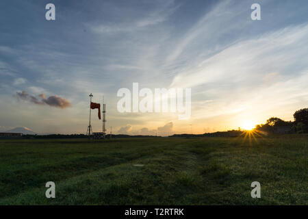 Sunrise all'aeroporto di Bali. Mattina vibes dal luminoso cielo chiaro. Aspetto di erba verde e guardare il calzino di vento, il vento è calmo Foto Stock