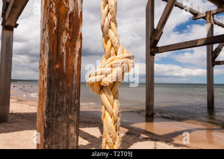 In prossimità di una spessa di colore arancio annodato la corda appesa da un molo su una spiaggia in Hartlepool nel nord est dell' Inghilterra Foto Stock