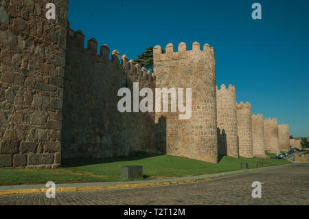 Fiancheggiata torri di pietra sulla grande parete della città in stile romanico accanto alla strada di Avila. Con un imponente muro intorno al quartiere Gotico della città in Spagna. Foto Stock