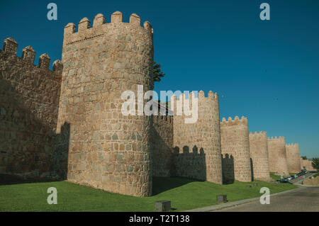 Fiancheggiata torri di pietra sulla grande parete della città in stile romanico accanto alla strada di Avila. Con un imponente muro intorno al quartiere Gotico della città in Spagna. Foto Stock