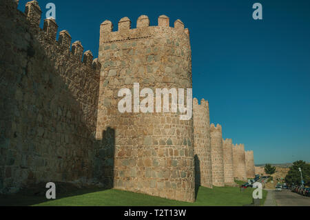 Fiancheggiata torri di pietra sulla grande parete della città in stile romanico accanto alla strada di Avila. Con un imponente muro intorno al quartiere Gotico della città in Spagna. Foto Stock