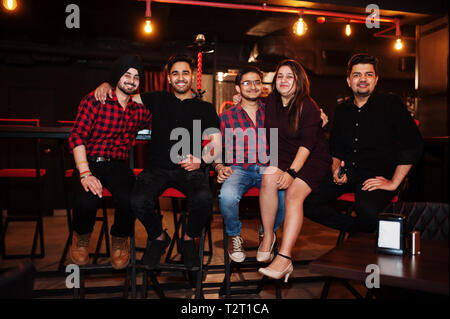 Gruppo di amici indiani seduti al lounge bar, divertimento e riposo. Foto Stock