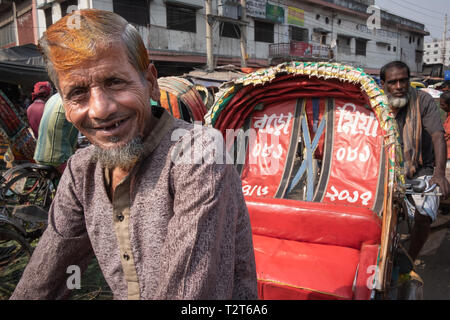 Sorridono felici rickshaw driver con faccia rugosa e rosso arancione henna capelli sulla trafficata strada di Dhaka, bloccato nel traffico Foto Stock