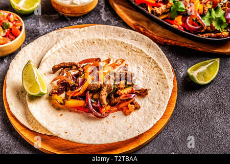 Le FAJITAS colorato con pepe e cipolle, servita con tortillas, salsa e panna acida. Foto Stock