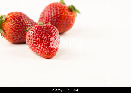 Close-up di tre fragole isolato su sfondo bianco shot in alto angolo di visione con il fuoco selettivo Foto Stock