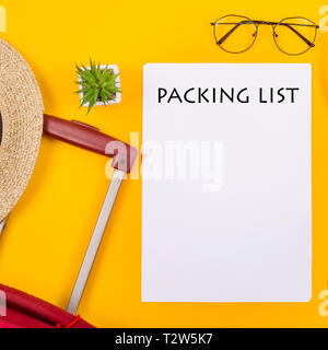 La lista di imballaggio per il viaggio è prossima ad una valigia, una tazza di caffè e una cannuccia estate borsa su uno sfondo giallo. Tenetevi pronti per un concetto di viaggio Foto Stock