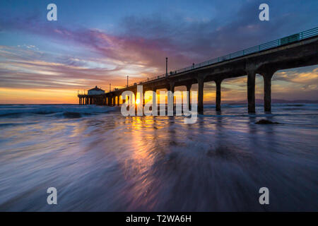 Lunga esposizione shot colorata del Cielo e nubi su Manhattan Beach Pier al tramonto con regolare lavaggio onde sulla spiaggia, Manhattan Beach, Californi Foto Stock