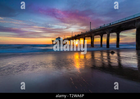 Lunga esposizione shot colorata del Cielo e nubi su Manhattan Beach Pier al tramonto con regolare lavaggio onde sulla spiaggia, Manhattan Beach, Californi Foto Stock