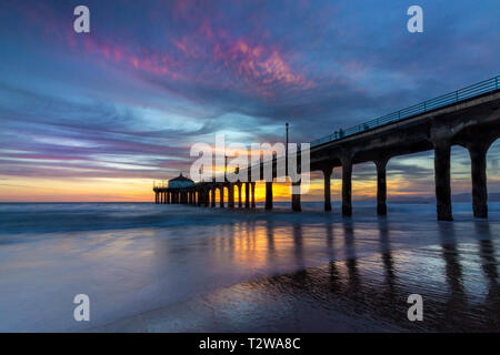 Lunga esposizione shot colorata del Cielo e nubi su Manhattan Beach Pier al tramonto con regolare lavaggio onde sulla spiaggia, Manhattan Beach, Californi Foto Stock