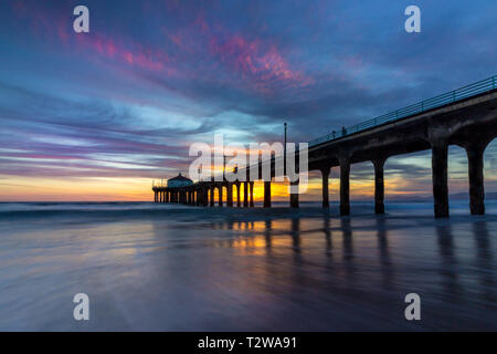 Lunga esposizione shot colorata del Cielo e nubi su Manhattan Beach Pier al tramonto con regolare lavaggio onde sulla spiaggia, Manhattan Beach, Californi Foto Stock