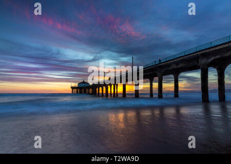 Lunga esposizione shot colorata del Cielo e nubi su Manhattan Beach Pier al tramonto con regolare lavaggio onde sulla spiaggia, Manhattan Beach, Californi Foto Stock