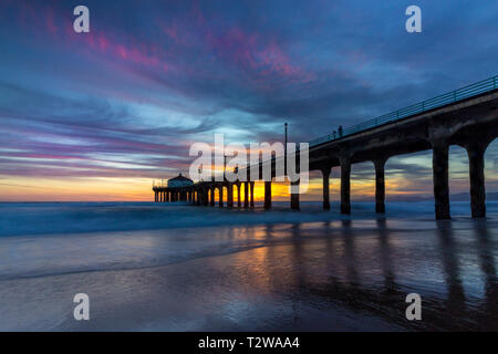 Lunga esposizione shot colorata del Cielo e nubi su Manhattan Beach Pier al tramonto con regolare lavaggio onde sulla spiaggia, Manhattan Beach, Californi Foto Stock