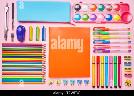 Composizione brillante da una scuola cartoleria su uno sfondo di colore rosa. Gruppo di forniture scolastiche sul tavolo. Concetto di educazione o di ritorno a scuola. Vista dall'alto, Foto Stock