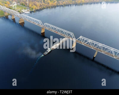 Scenic aerial cityscape di Kiev e il fiume Dnipro al tramonto. Rimorchiatore chiatta di supporto con sabbia di materiali alla rinfusa voce lungo il fiume Dnieper. In Ucraina Foto Stock