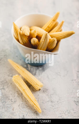 Fresca giovani baby corn sul cemento grigio sfondo Foto Stock