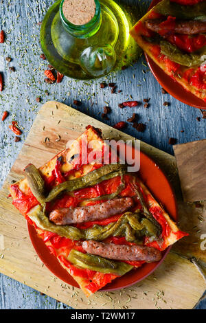 Angolo di alta vista di una fetta di coca de recapte, tipica catalana torta salata simile alla pizza fatta con melanzane alla griglia e pepe rosso e salsicce, Foto Stock