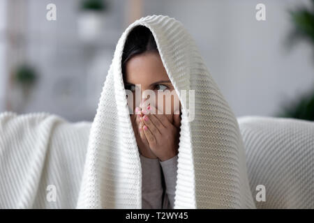 Donna con coperte plaid bianco riscaldare le mani con il respiro Foto Stock