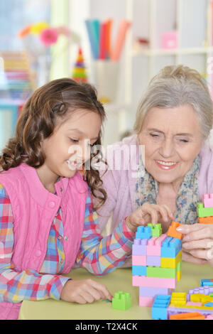 Curly bambina e la nonna a giocare con colorati di materia plastica in blocchi Foto Stock