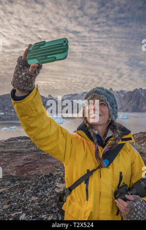 Donna prendendo un selfie con un telefono cellulare, Scoresbysund, Groenlandia Foto Stock
