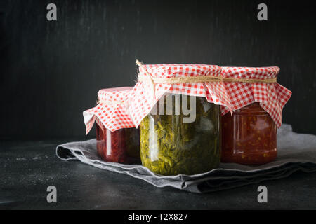 Vari tipi di conserve di salsa fatta in casa per servire alla carne, adjika dal pomodoro, sorrel, tkemali dalla prugna. Preparati in casa, compiti e traditi Foto Stock