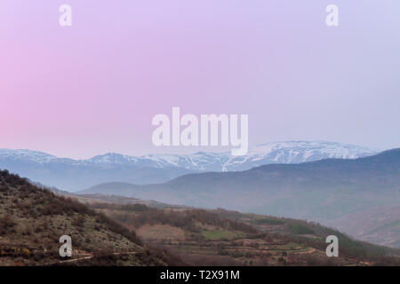 Distanza coperta di neve Midzor vertice sulla vecchia montagna durante ore blu e morbida, cielo viola Foto Stock