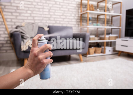 Close-up di un essere umano di spruzzatura manuale profumatore in salotto Foto Stock