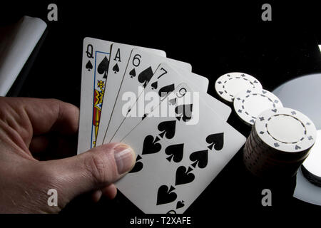 Gioca a poker da vicino. Carte di essere tenuto in una mano di poker chips blakc tabella. Foto Stock