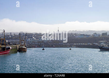 Howth Harbour a Dublino in Irlanda con le attività di pesca i pescherecci con reti da traino legato e nuvole in rotolamento sulla Howth Head,. Foto Stock