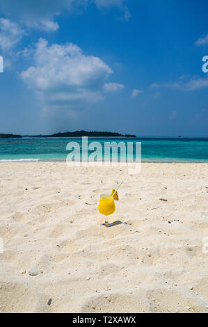 Cocktail di frutta su di una spiaggia di sabbia con acqua blu - Maldive Foto Stock