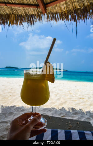 Cocktail di frutta su di una spiaggia di sabbia con acqua blu - Maldive Foto Stock