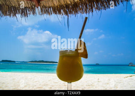 Cocktail di frutta su di una spiaggia di sabbia con acqua blu - Maldive Foto Stock