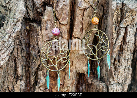 Orecchini di metallo sul naturale sfondo di legno Foto Stock
