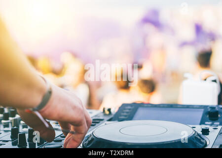 Close up DJ mano riproduzione di musica a torretta su un beach party festival - Ritratto di DJ Mixer audio in un beach club sopra la folla dancing Foto Stock