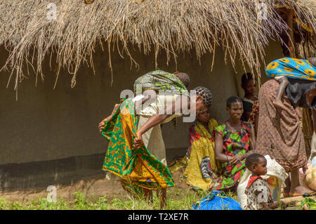 Donna che fissano il bambino sulla schiena in villaggio Malawi Foto Stock