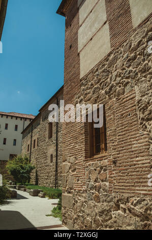 Le vecchie case di pietra e mattoni su un vicolo deserta, in una giornata di sole a Avila. Con un imponente muro intorno al quartiere Gotico della città in Spagna. Foto Stock