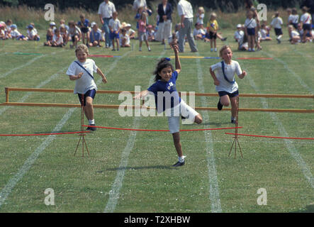 I bambini della scuola elementare in competizione in corsa ad ostacoli durante la giornata dello sport Foto Stock