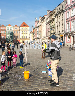 Bambini I ragazzi e le ragazze di guardare un animatore di strada in lastricato della piazza della città vecchia nella città polacca di Poznan in Polonia Foto Stock