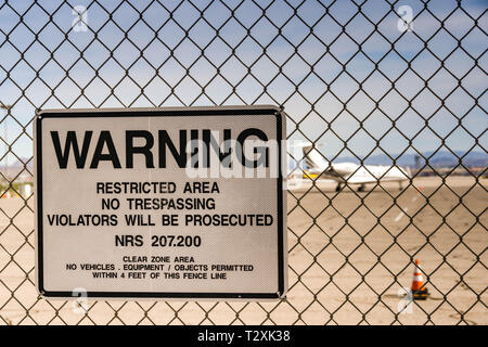 LAS VEGAS, NEVADA, STATI UNITI D'AMERICA - Febbraio 2019: Segno di avvertimento su un recinto intorno all'Aeroporto Internazionale McCarran. In fondo è un private jet executive. Foto Stock
