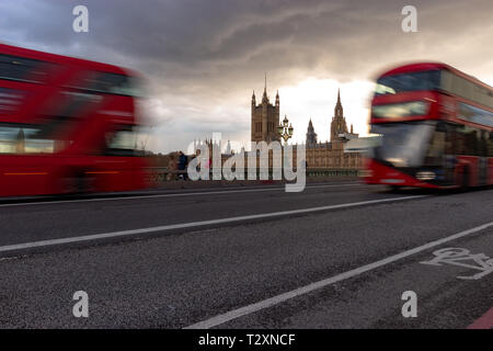 Westminster, Londra, Inghilterra, 3 aprile 2019. Famosi autobus rossi che viaggiano in direzioni opposte attraverso Westminster Bridge con le case del Parlamento Foto Stock