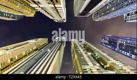 (Prospettiva diversa) Splendida vista dal basso verso l'alto di alcuni alti grattacieli e torri accesa durante la notte in Marina di Dubai. Foto Stock